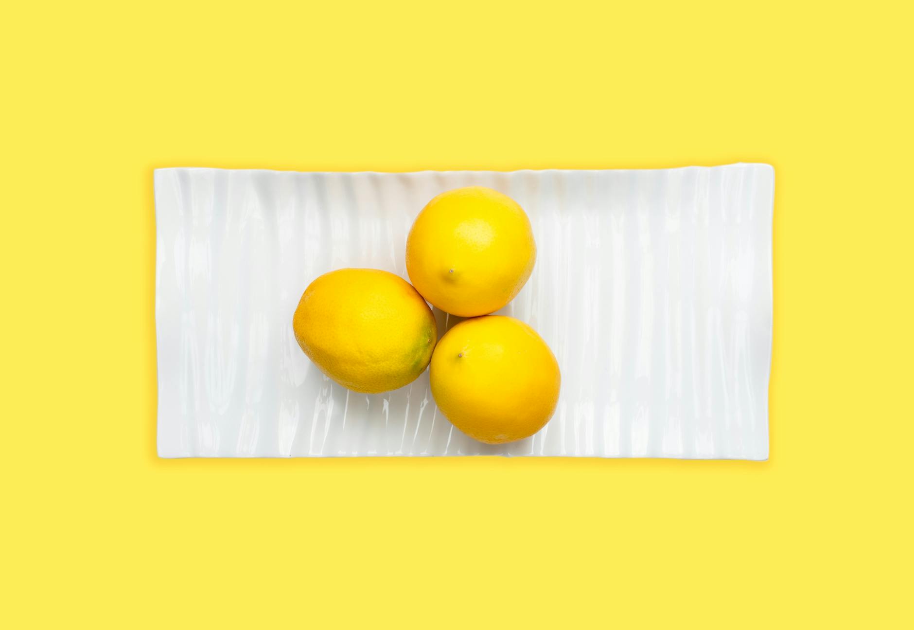 Fresh lemons arranged on white plate with bright yellow background, symbolizing openness and refreshing approach to couple communication