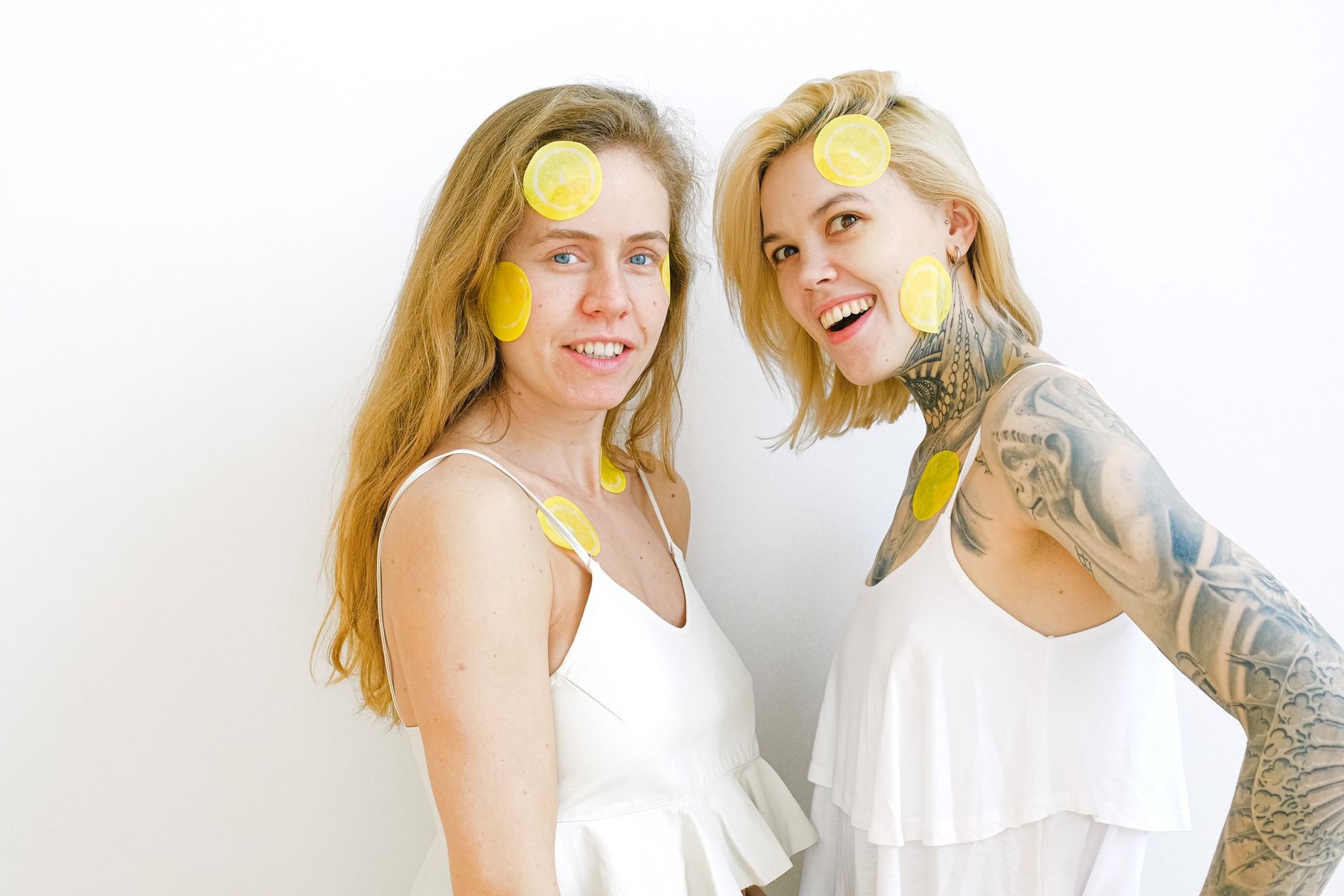 Blue vibrator surrounded by flowers and citrus slices on yellow background