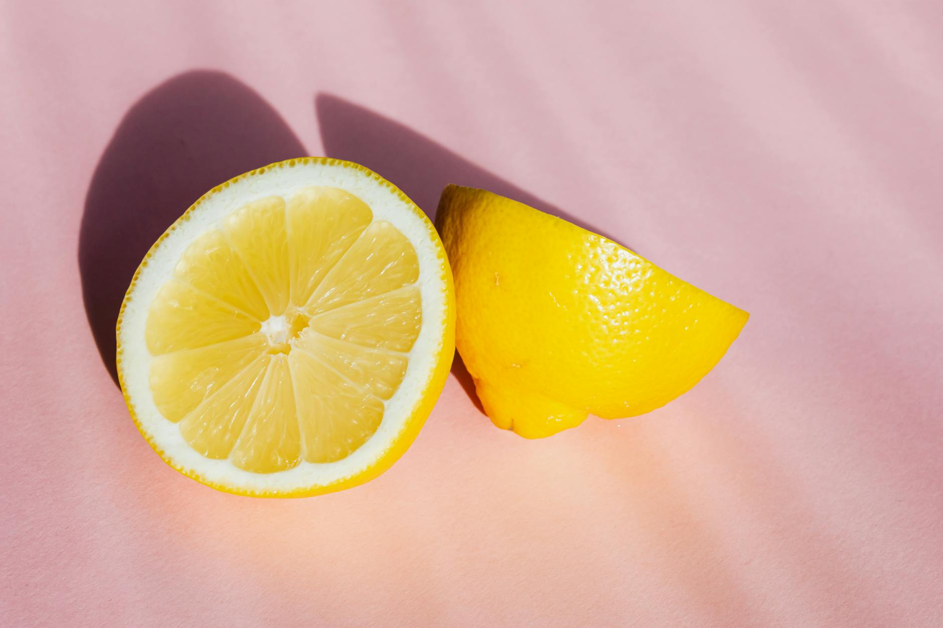 Fresh lemons on a pink background in sunlight, representing the natural cycles that affect sensitivity