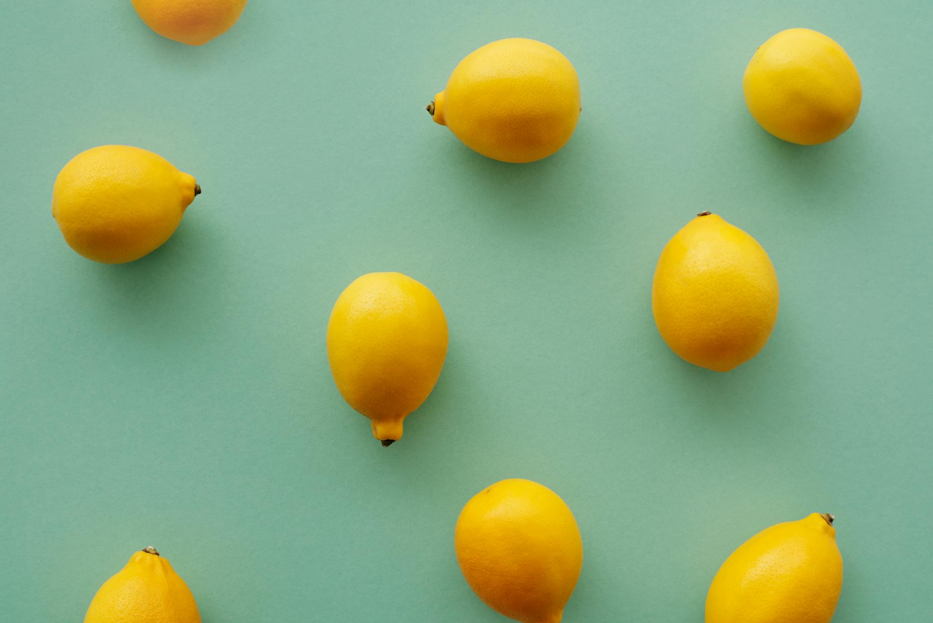 Bright yellow lemons on a soft green background, symbolizing refreshed sensation and renewed pleasure.