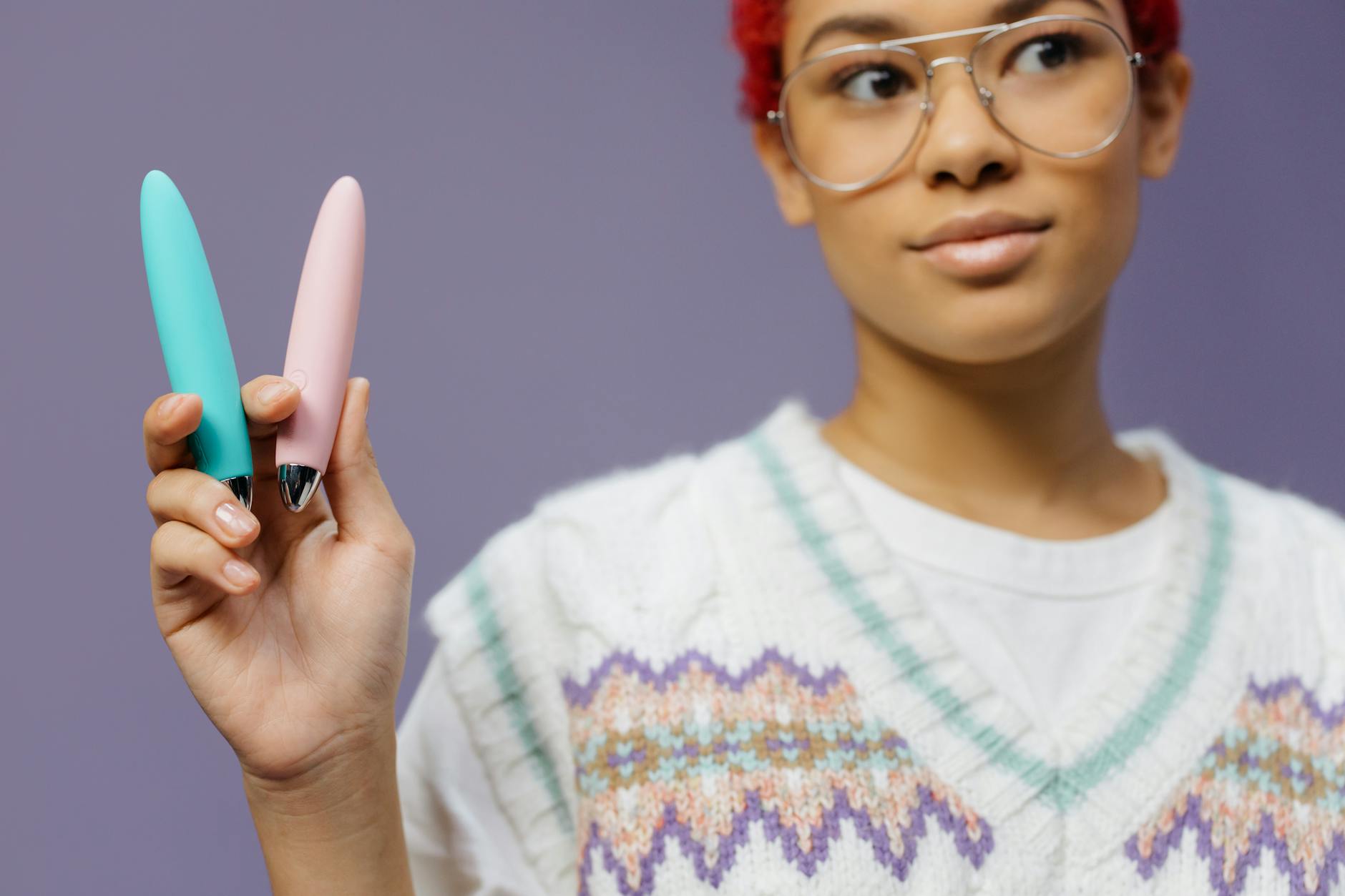 Hands holding a colorful silicone lemon vibrator against a neutral background