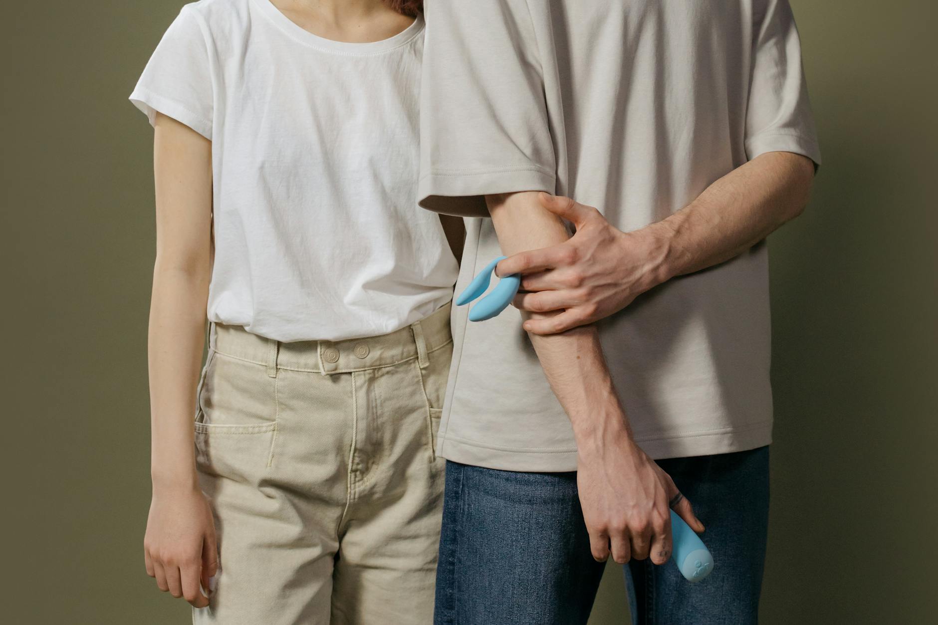 A blue silicone clitoral vibrator held in hand against a purple background, representing self-pleasure and modern intimacy
