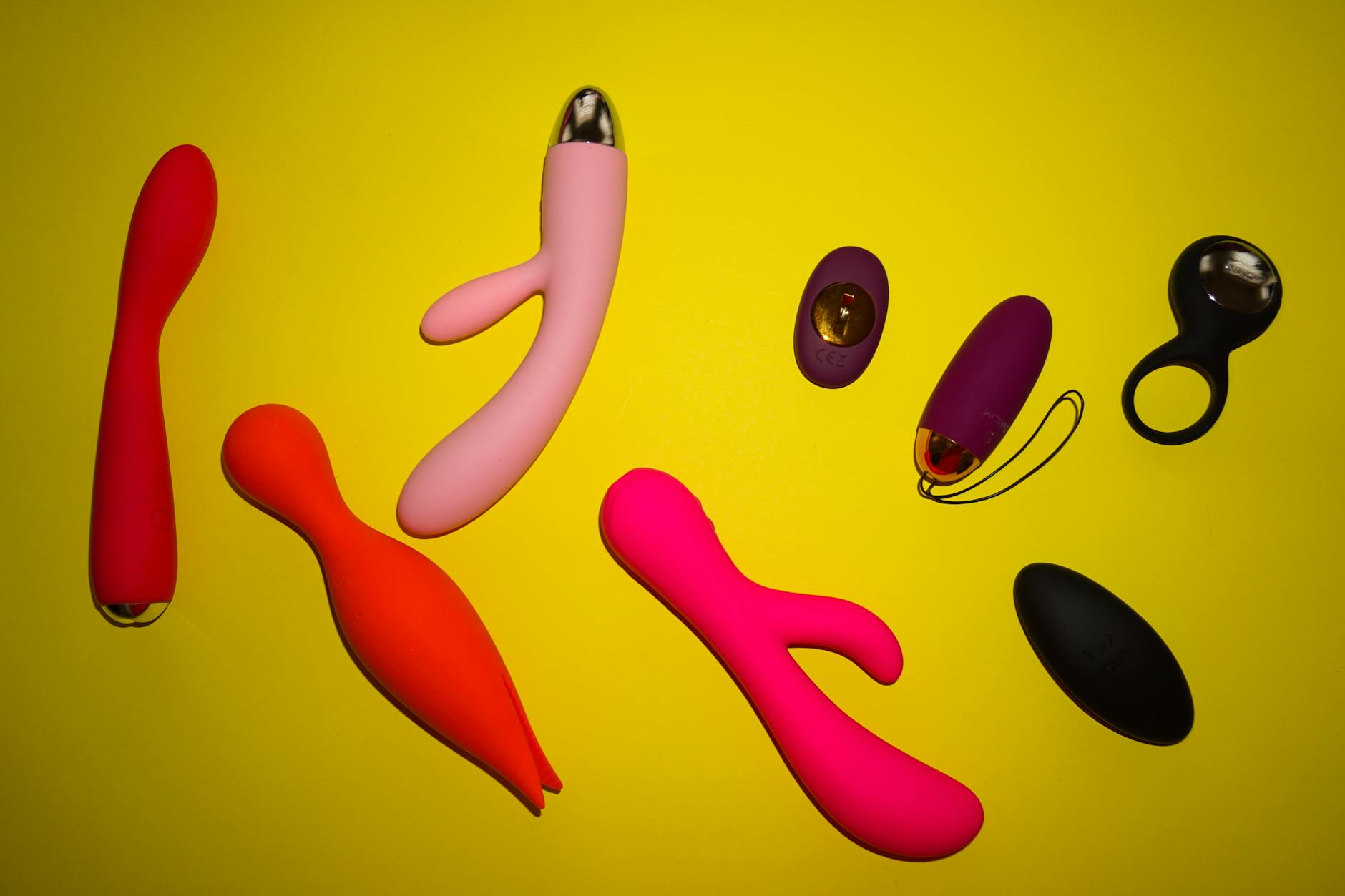 Colorful silicone vibrators arranged on a bright yellow surface