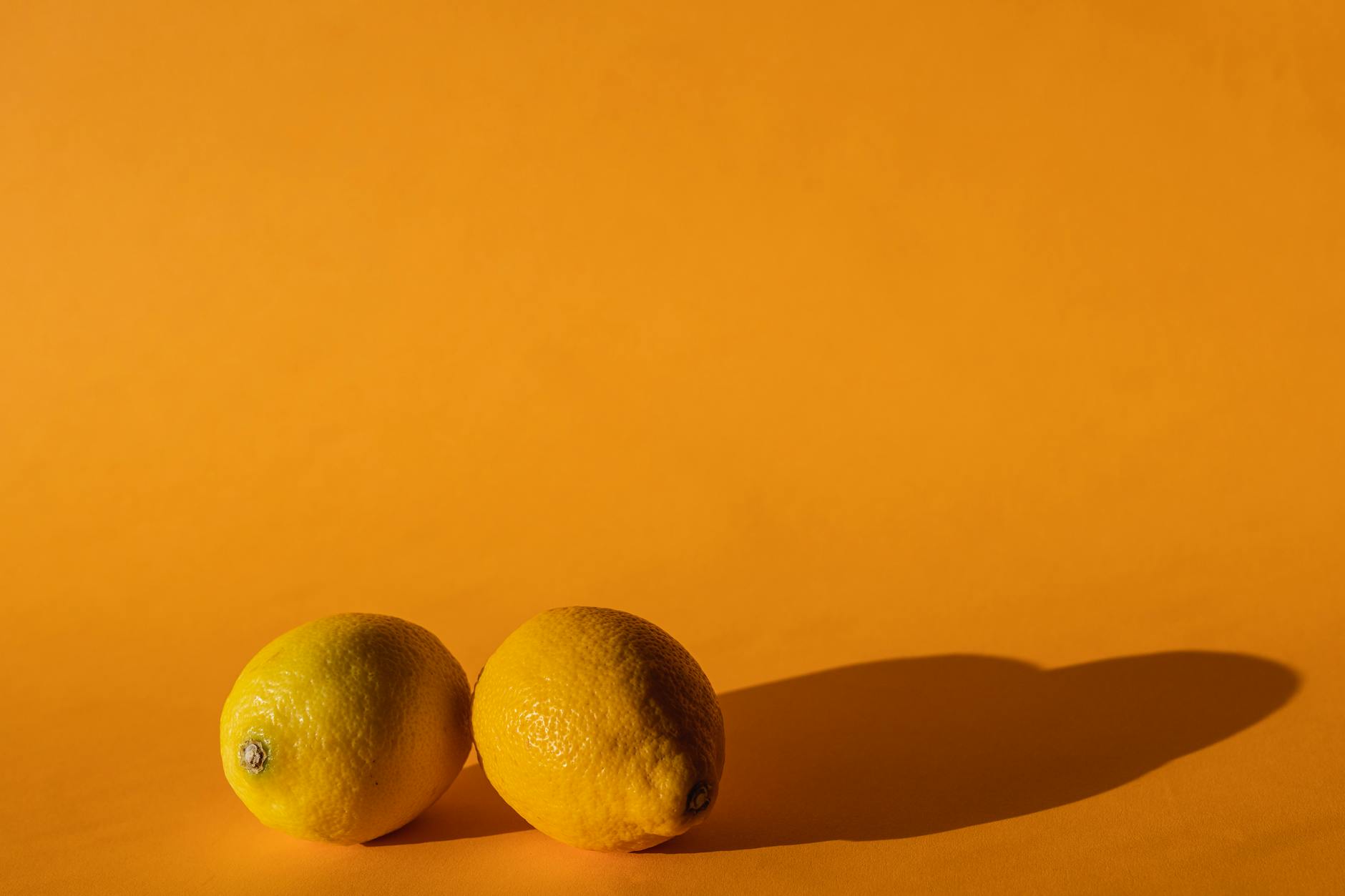 Close-up of hands holding a sleek lemon vibrator against a purple background